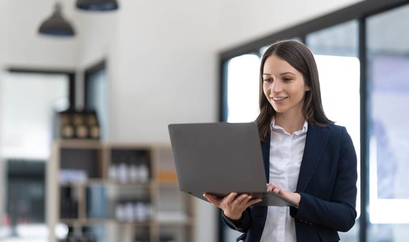 Asian young female professional businesswoman secretary employee in formal suit at working desk typing report via laptop notebook computer