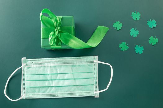 St Patricks Day. overhead flat lay of paper cut clover leaves festive decor and Medical face mask, shamrocks leaf holiday symbol on colour background, New normal for coronavirus