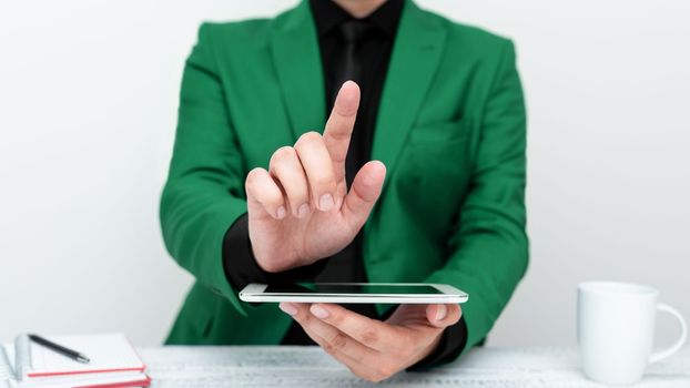 Businessman in a Green jacket sitting at a table holding a mobile phone