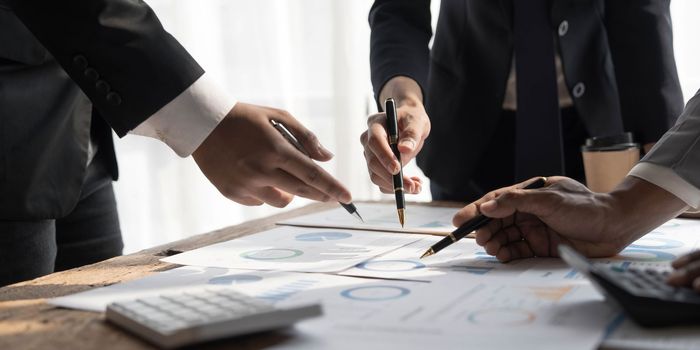 Business People Meeting using laptop computer,calculator,notebook,stock market chart paper for analysis Plans to improve quality next month.