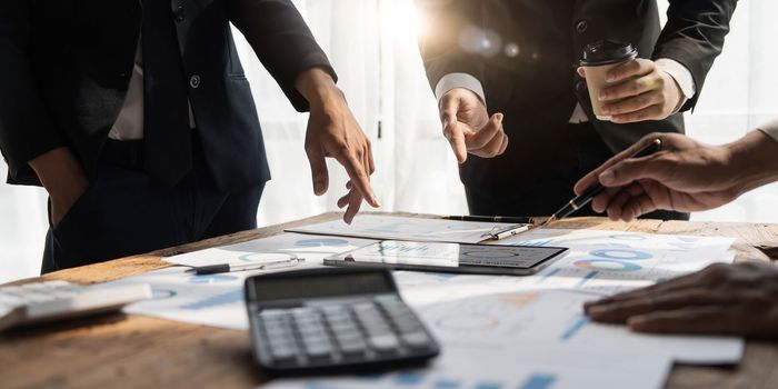 Business People Meeting using laptop computer,calculator,notebook,stock market chart paper for analysis Plans to improve quality next month.