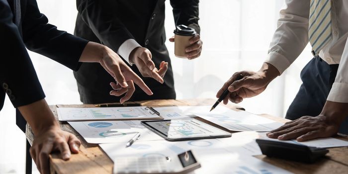 Business People Meeting using laptop computer,calculator,notebook,stock market chart paper for analysis Plans to improve quality next month.