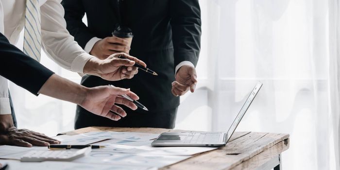 Business People Meeting using laptop computer,calculator,notebook,stock market chart paper for analysis Plans to improve quality next month.