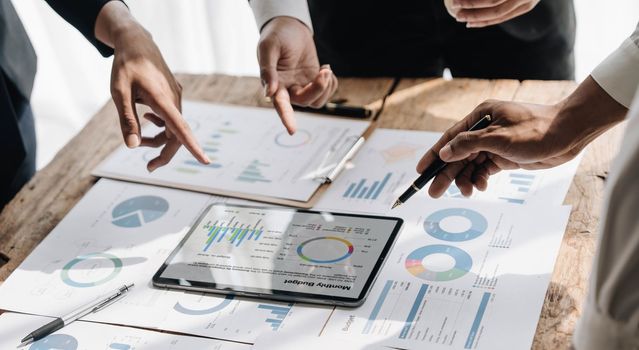 Business People Meeting using laptop computer,calculator,notebook,stock market chart paper for analysis Plans to improve quality next month.