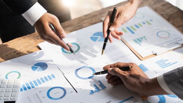 Business People Meeting using laptop computer,calculator,notebook,stock market chart paper for analysis Plans to improve quality next month.