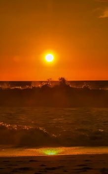 Beautiful stunning colorful and golden sunset in yellow orange red on beach and big wave panorama in tropical nature in Zicatela Puerto Escondido Oaxaca Mexico.