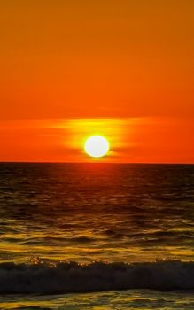 Beautiful stunning colorful and golden sunset in yellow orange red on beach and big wave panorama in tropical nature in Zicatela Puerto Escondido Oaxaca Mexico.