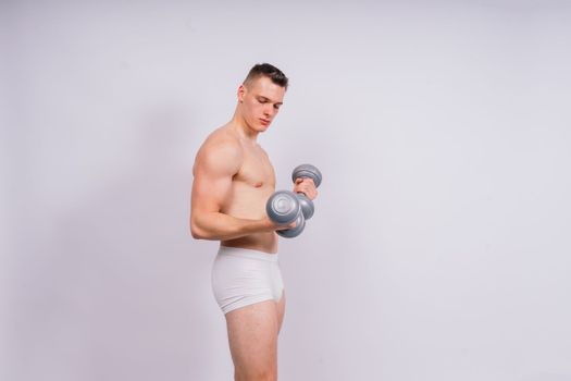 Shirtless bodybuilder holding a dumbell and showing his muscular arms.