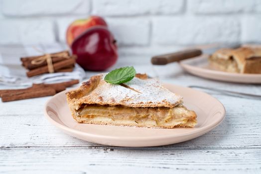 Autumn food. Homemade piece of apple pie with fresh red apples on white dining tabl