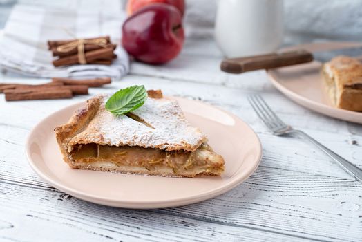 Autumn food. Homemade piece of apple pie with fresh red apples on white dining tabl