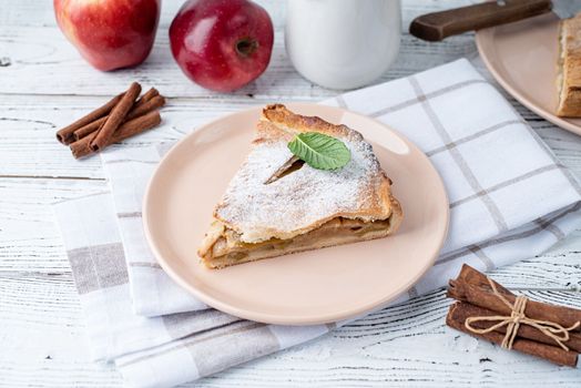 Autumn food. Homemade piece of apple pie with fresh red apples on white dining tabl