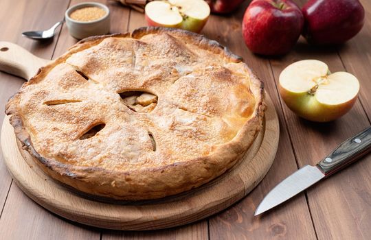 Autumn food. Homemade apple pie with fresh red apples on wooden table