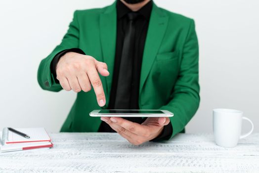 Businessman in a Green jacket sitting at a table holding a mobile phone