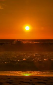 Beautiful stunning colorful and golden sunset in yellow orange red on beach and big wave panorama in tropical nature in Zicatela Puerto Escondido Oaxaca Mexico.