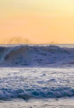 Beautiful stunning colorful and golden sunset in yellow orange red on beach and big wave panorama in tropical nature in Zicatela Puerto Escondido Oaxaca Mexico.