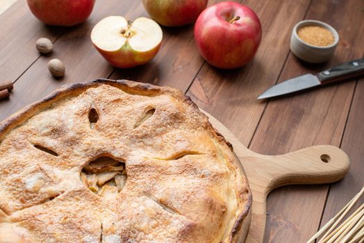 Autumn food. Homemade apple pie with fresh red apples on wooden table