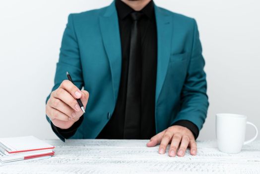 Male mode sitting at table And Pointing With Pen On Important Message.