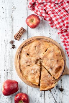 Autumn food. Homemade apple pie with slice with fresh red apples on wooden table