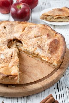 Autumn food. Homemade apple pie with slice with fresh red apples on wooden table