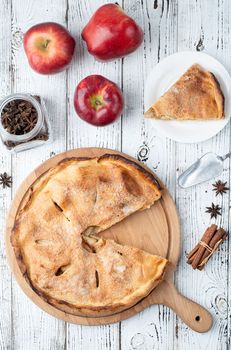 Autumn food. Homemade apple pie with slice with fresh red apples on wooden table