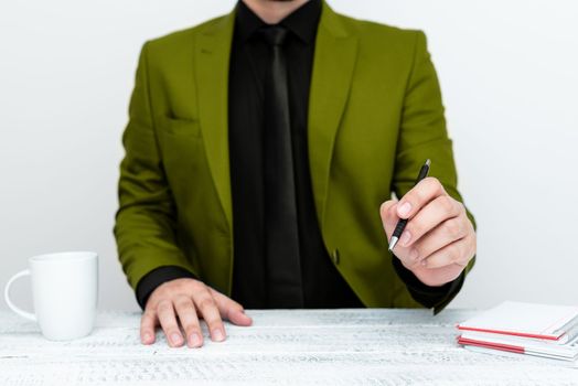 Male mode sitting at table And Pointing With Pen On Important Message.