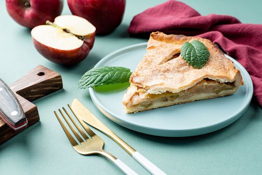 Autumn food. Homemade piece of apple pie with fresh red apples on green table