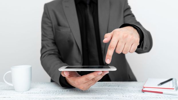 Businessman in a gray jacket sitting at a table holding a mobile phone