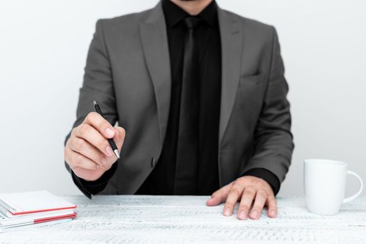 Male model in suit sitting at table And Pointing With Pen On Message.