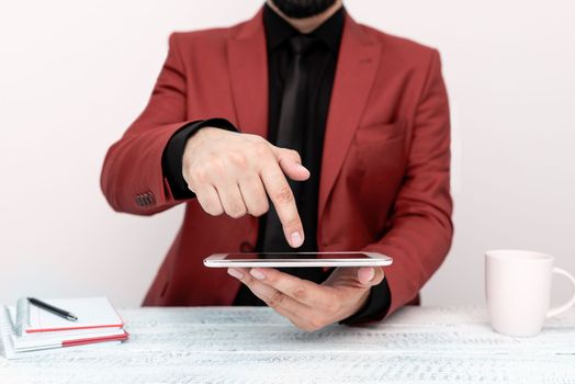 Businessman in a Red jacket sitting at a table holding a mobile phone