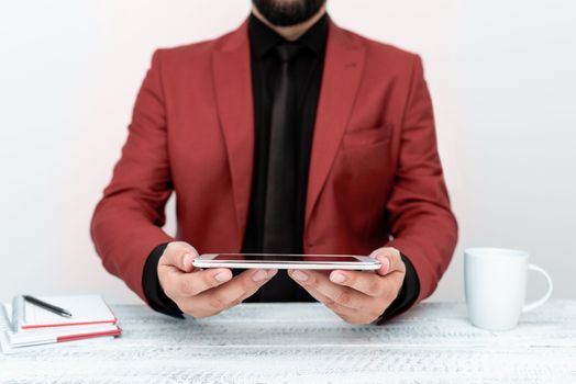 Businessman in Red jacket sitting at a table and holding a mobile phone.