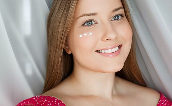 Beautiful woman with skincare cream on her face.