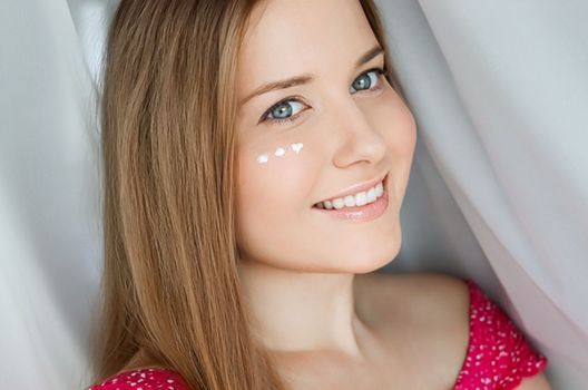 Beautiful woman with skincare cream on her face.