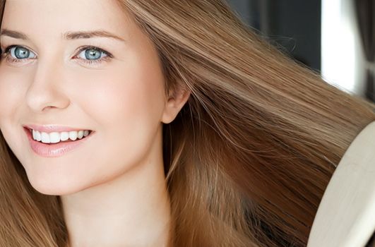 Beautiful happy woman combing her long hair.