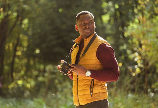 African american guy photographer taking picture with vintage camera on city green park - leisure activity, diversity and hobby