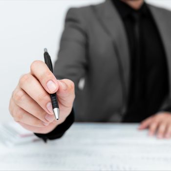 Male mode sitting at table And Pointing With Pen On Important Message.