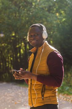 African american man listens music in spring park. Gadget, app and streaming service concep