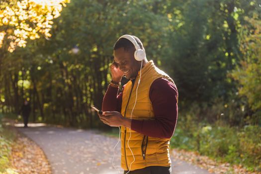 African american man listens music in spring park. Gadget, app and streaming service concep