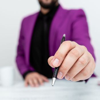 Male mode sitting at table And Pointing With Pen On Important Message.