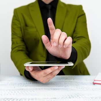 Businessman in a Green jacket sitting at a table holding a mobile phone