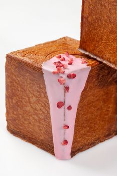 Closeup of puff pastry cube shaped croissant topped with sweet creamy berry sauce and candied raspberry crumble isolated on white background. Delicate French style treat