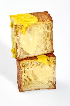 Sliced fluffy and crispy cube shaped croissant with delicate filling of vanilla custard cream topped with yellow glaze of white chocolate and chocolate chips. Delicious sweet French style pastries