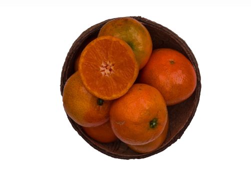 Fresh orange in a coconut shell on a white background.