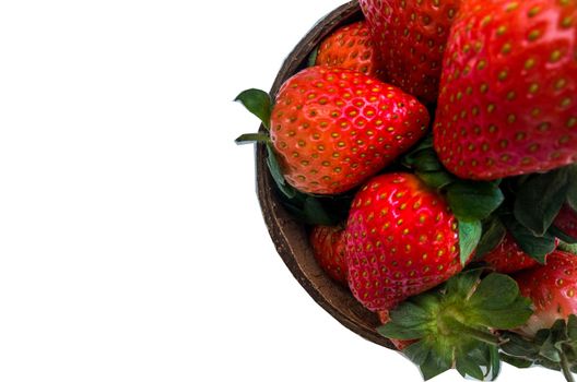 Fresh strawberries in a coconut shell on white background.