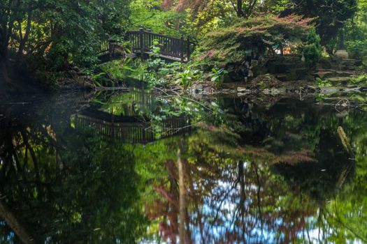 arched wooden bridge over ornamental garden pond, beautiful