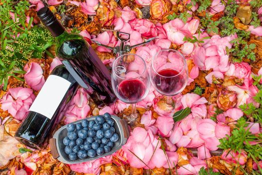 bottles, wine glasses with blueberry in rose garden.