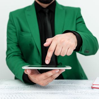 Businessman in a Green jacket sitting at a table holding a mobile phone