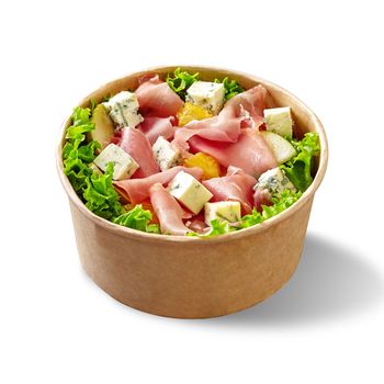 Paper bowl of piquant salad with fresh lettuce, blue cheese, thinly sliced prosciutto, sweet pear and juicy orange topped with mustard dressing isolated on white background. Takeaway food concept