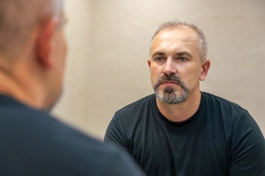 Middle-aged handsome man looking in mirror in a bathroom after shaving