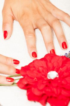 Hands of a woman with red nail polish posed by an esthetician