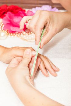 The beautician polish the client's nails before putting nail polish